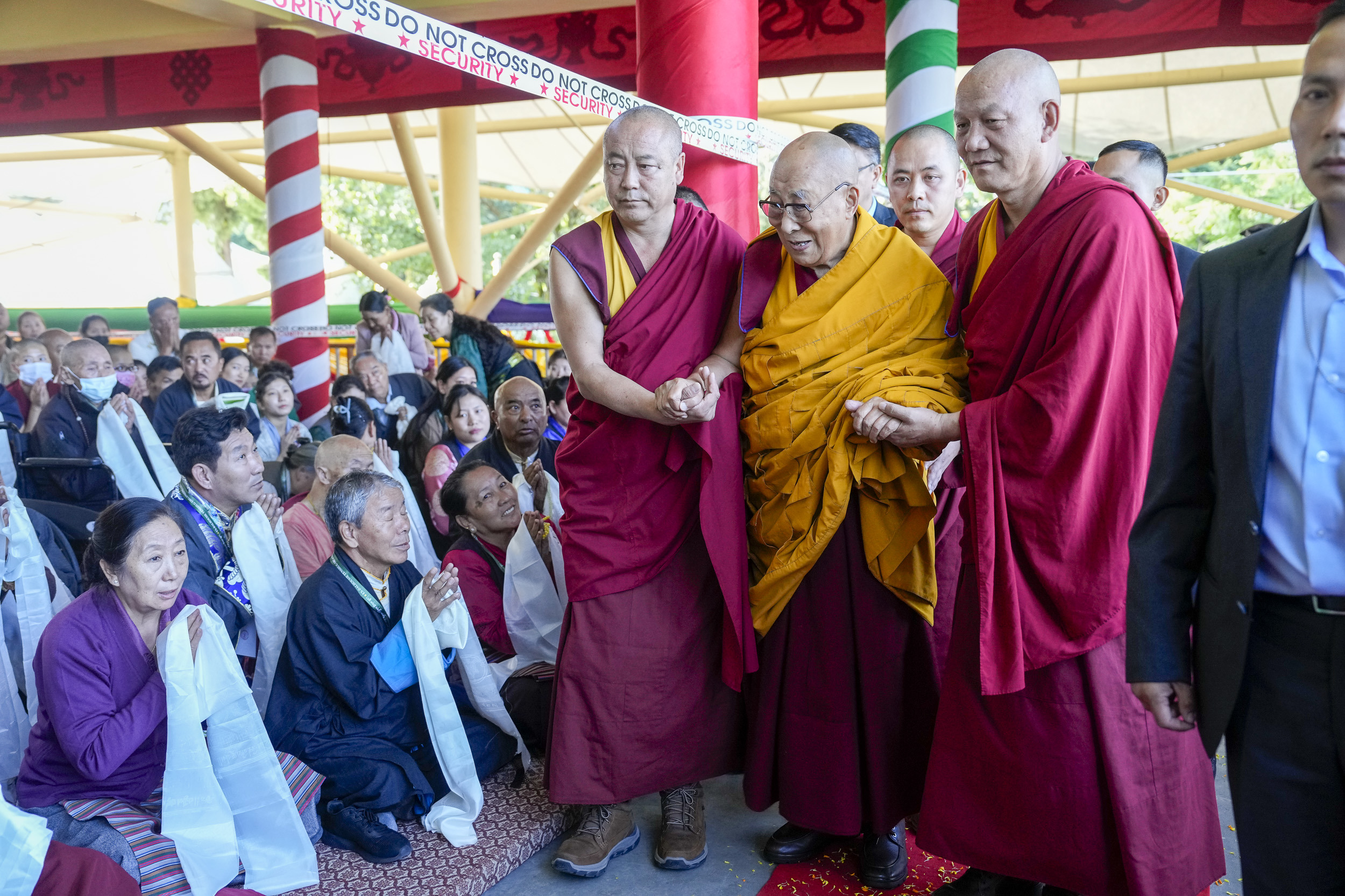 Зураг. Дээрхийн гэгээн Далай лам Намжал дацангийн Зүглэгхан дуганд болох бат оршил өргөх ёслолд оролцохоор морилох замдаа цугласан олонтой эелдэг дотноор харилцан мэндчилж буй нь... Энэтхэг, Химачал Прадеш муж, Дарамсала хот. 2024 оны 9 дүгээр сарын 18. Гэрэл зургийг Дэнзин Чойжир.